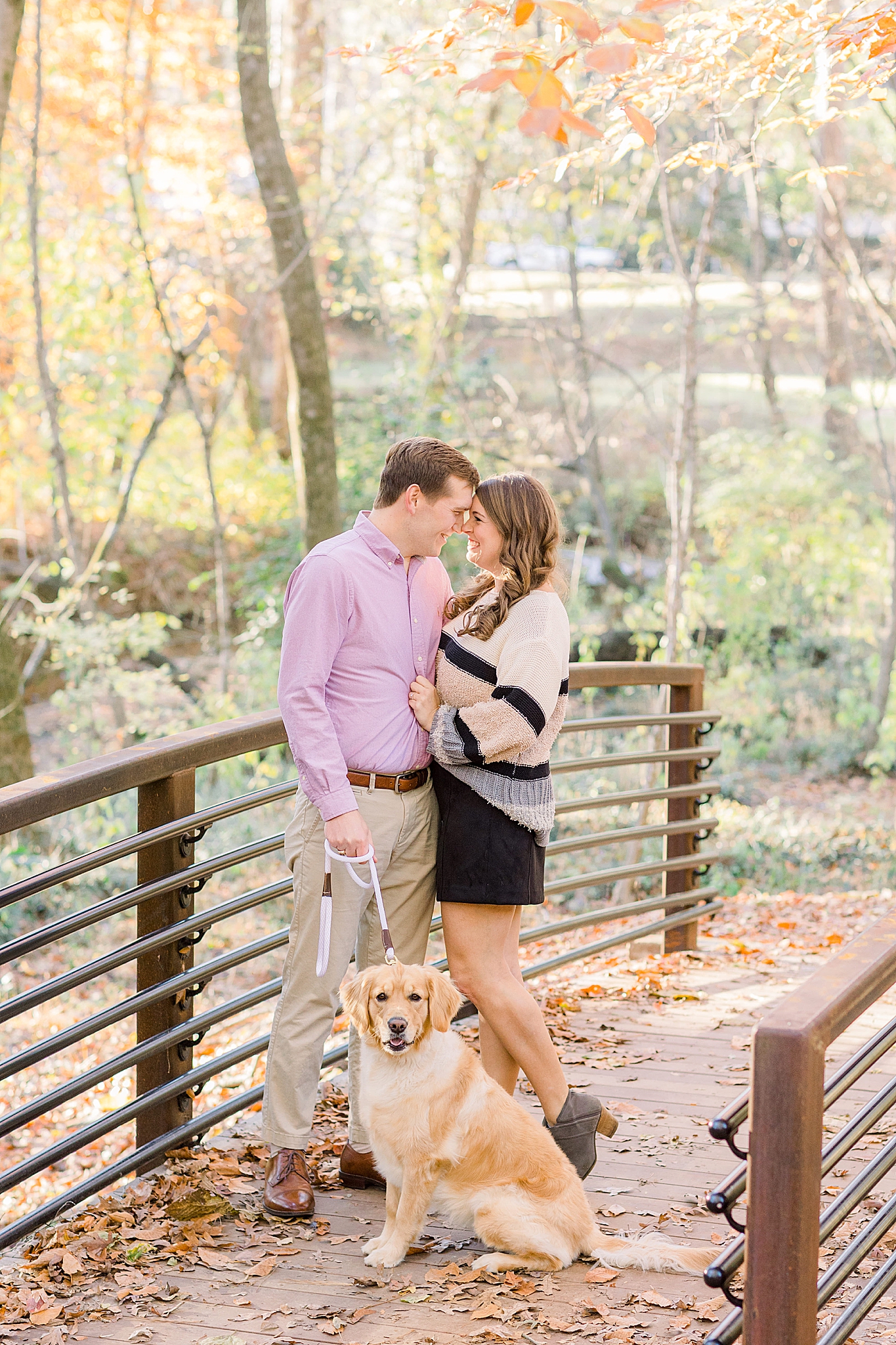engaged couple poses on bridge covered in leaves during Jemison park engagement photos