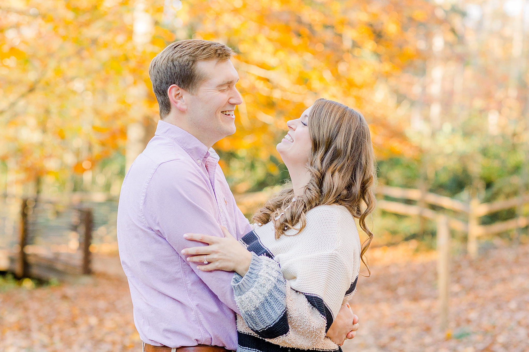 bride and groom laugh in front of orange and yellow trees