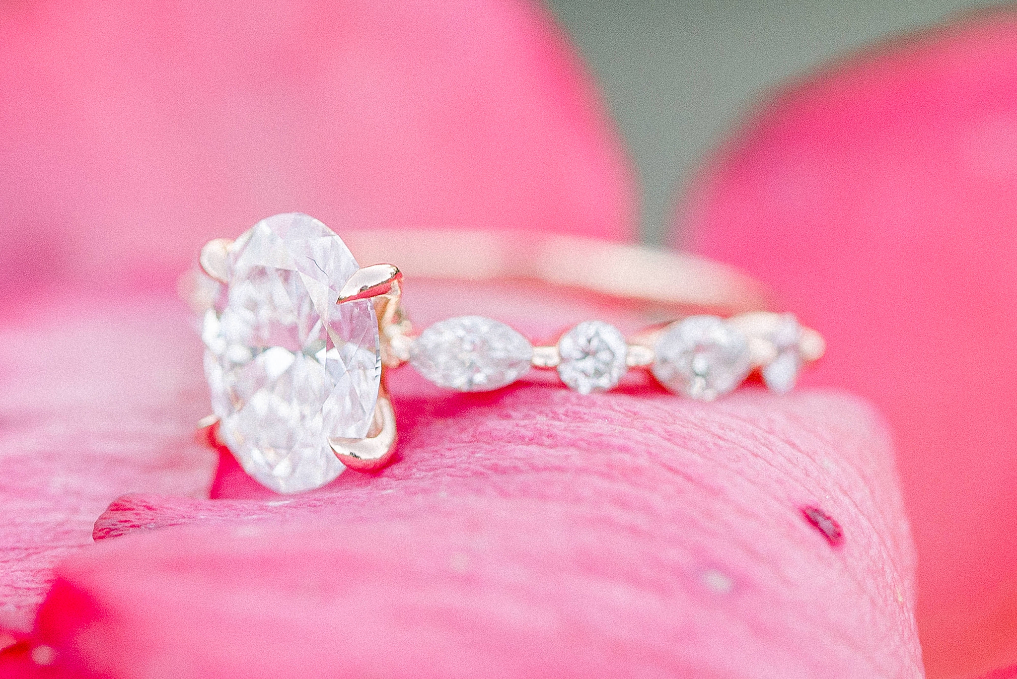 engagement ring rests on pink petal