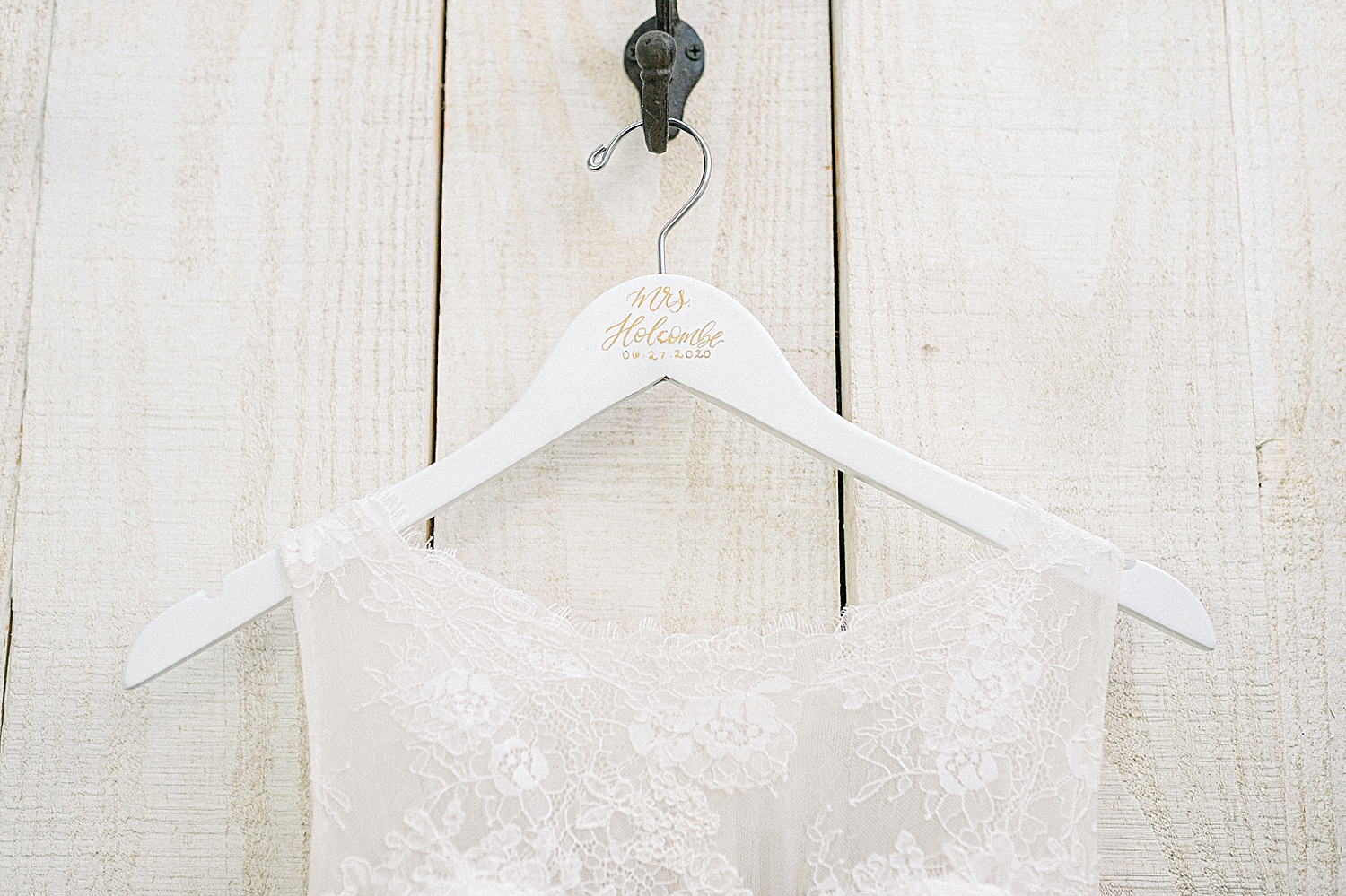 bride's dress hangs on white wooden hanger