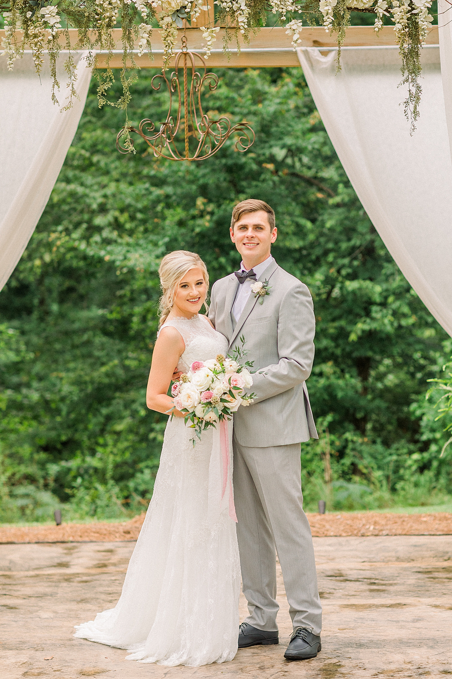 bride and groom pose together by pergola at Creekside Meadows