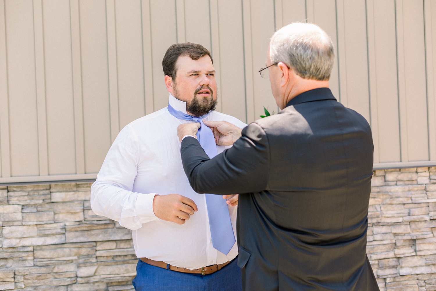 father of groom adjusts tie