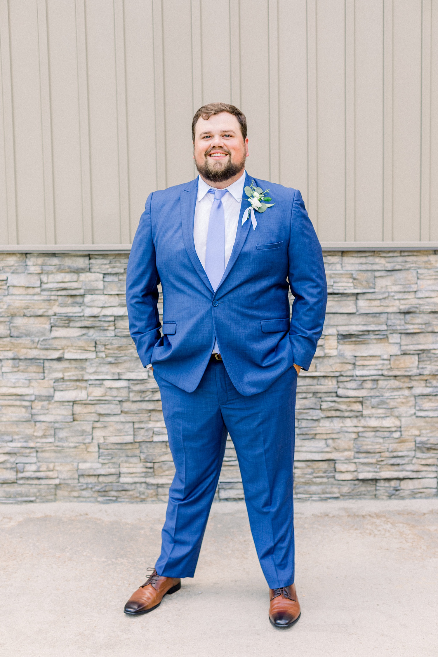 groom in navy blue suit poses outside Douglas Manor