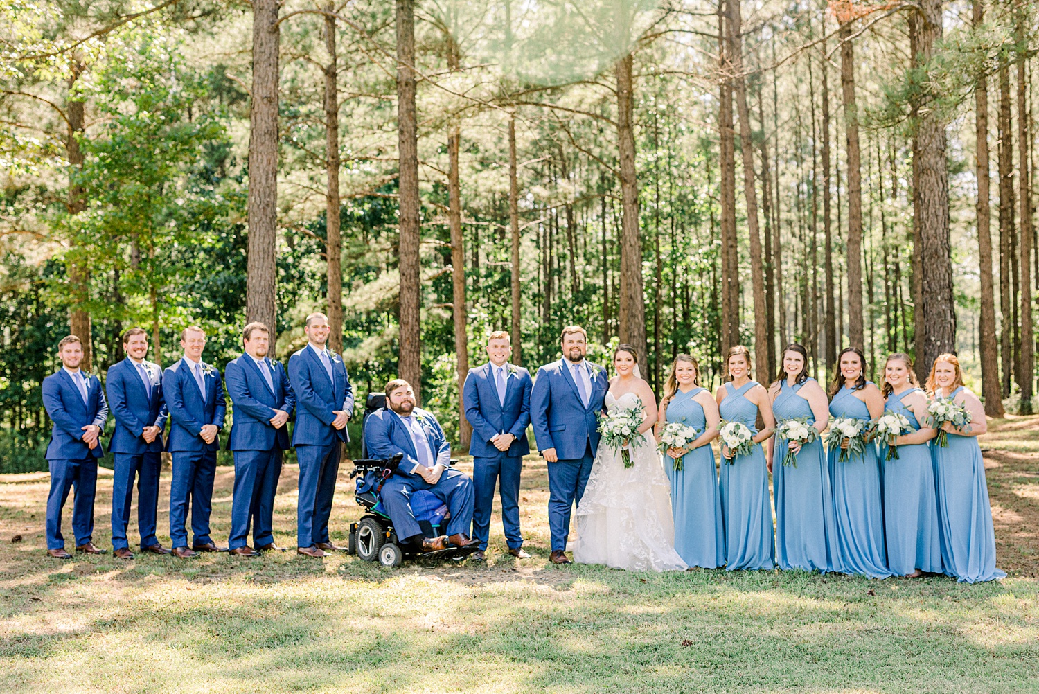 bridal party in blue poses with bride and groom during Douglas Manor wedding photos