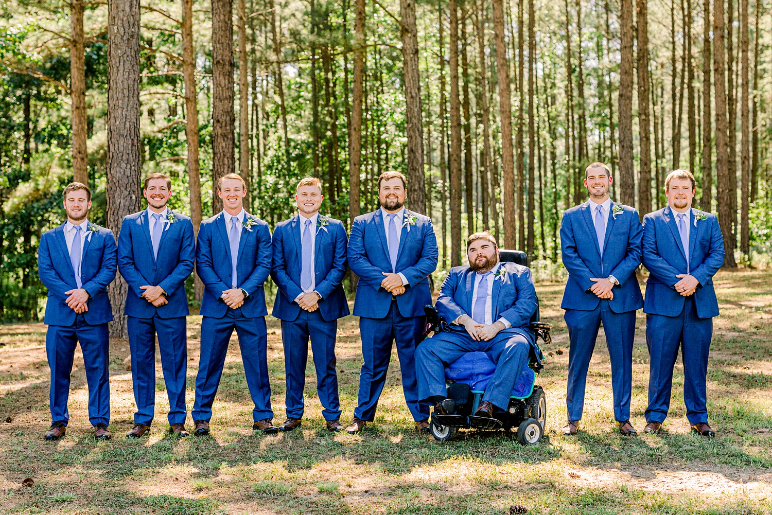 groom poses with groomsmen in blue suits