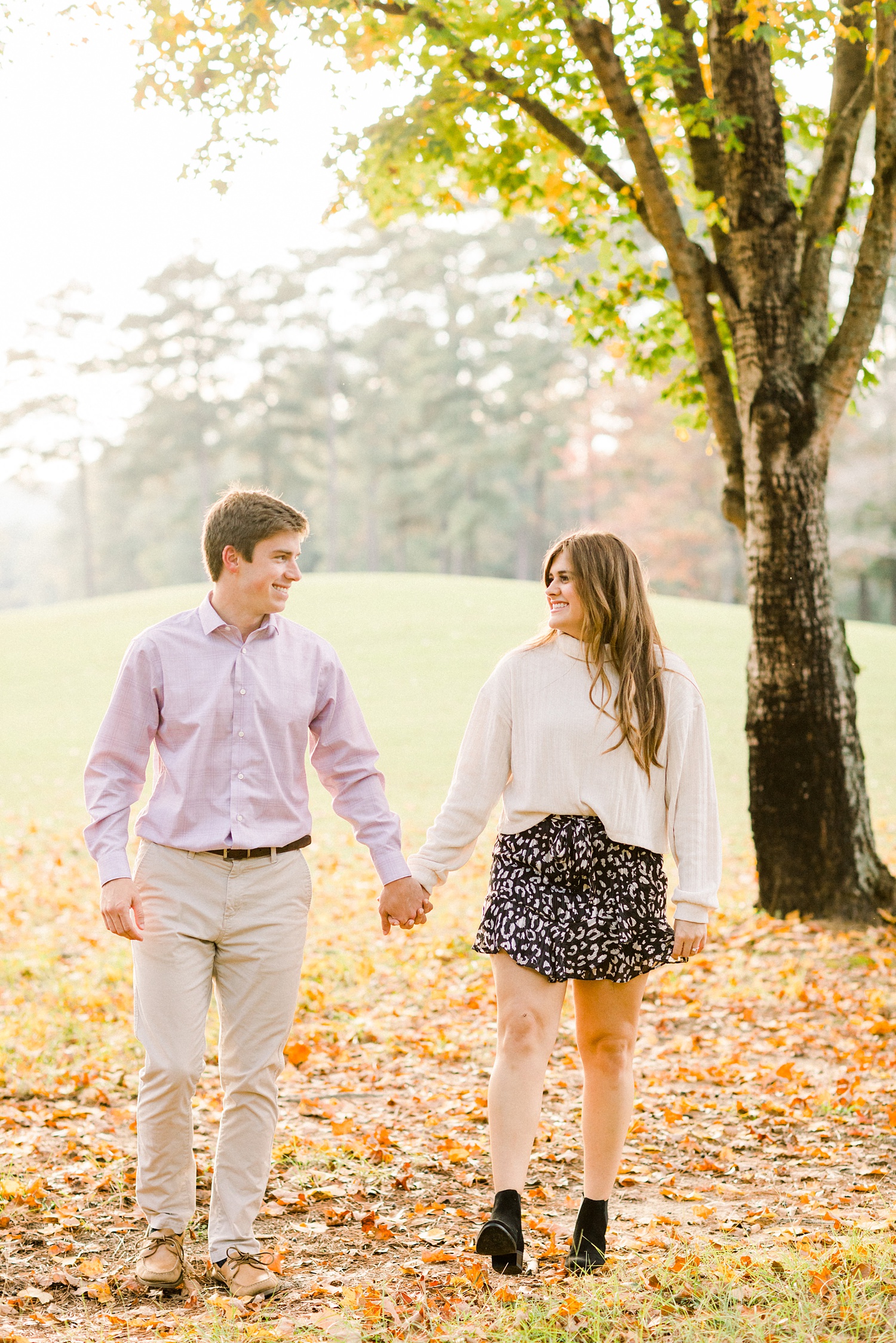 engaged couple walks through fallen leaves in Birmingham AL