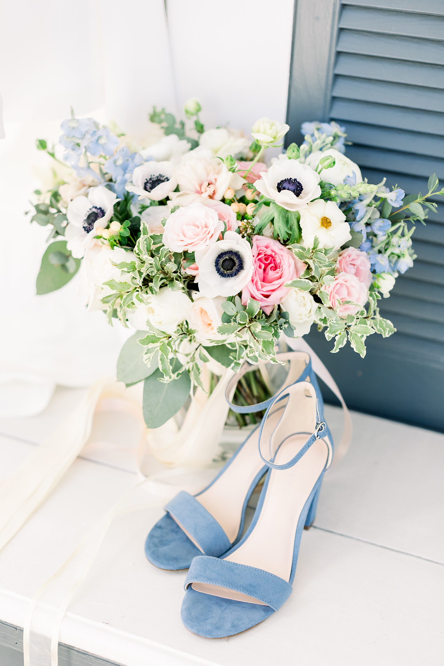 bridal bouquet rests against window with blue shoes
