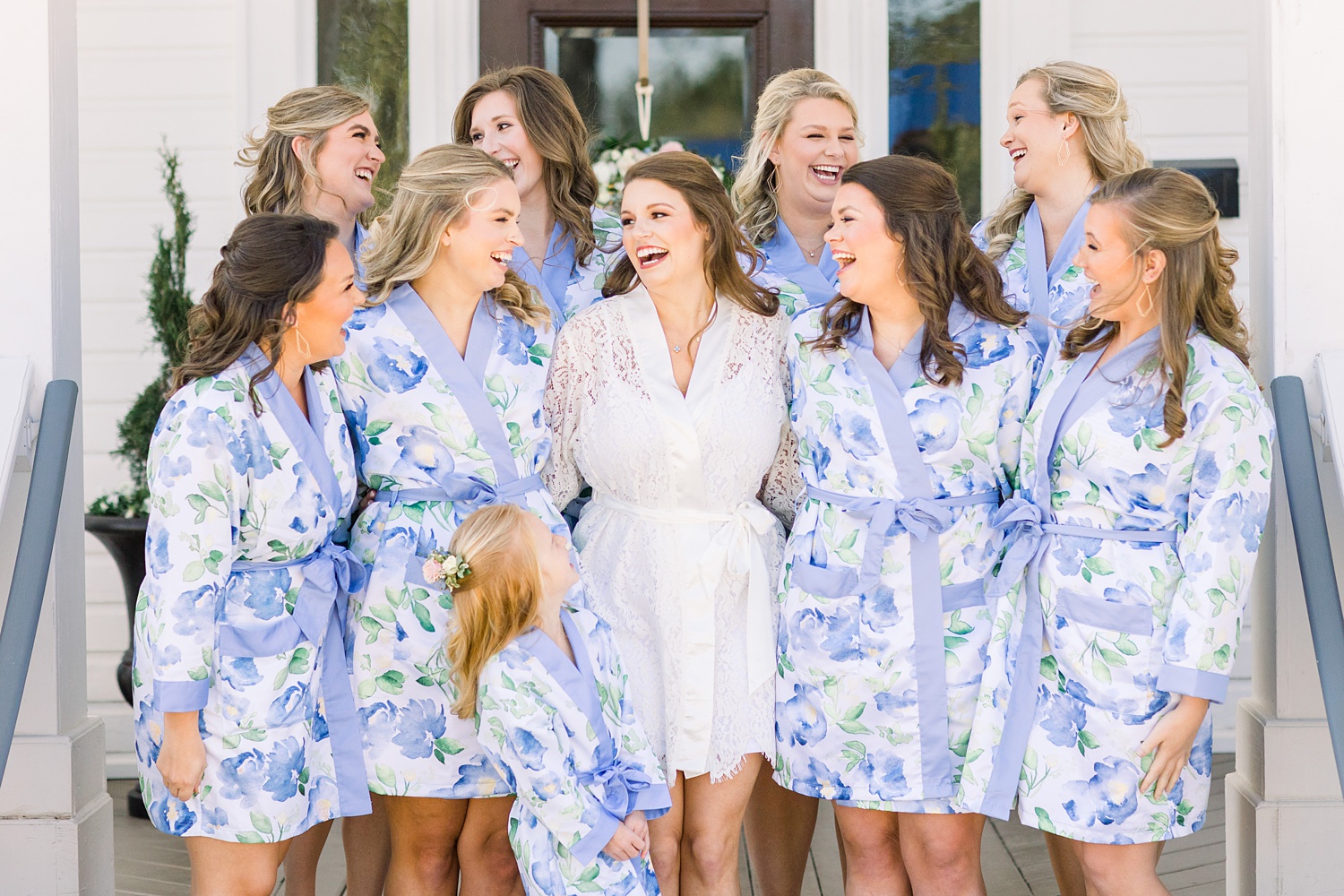 bride and bridesmaids in blue robes laugh during wedding morning
