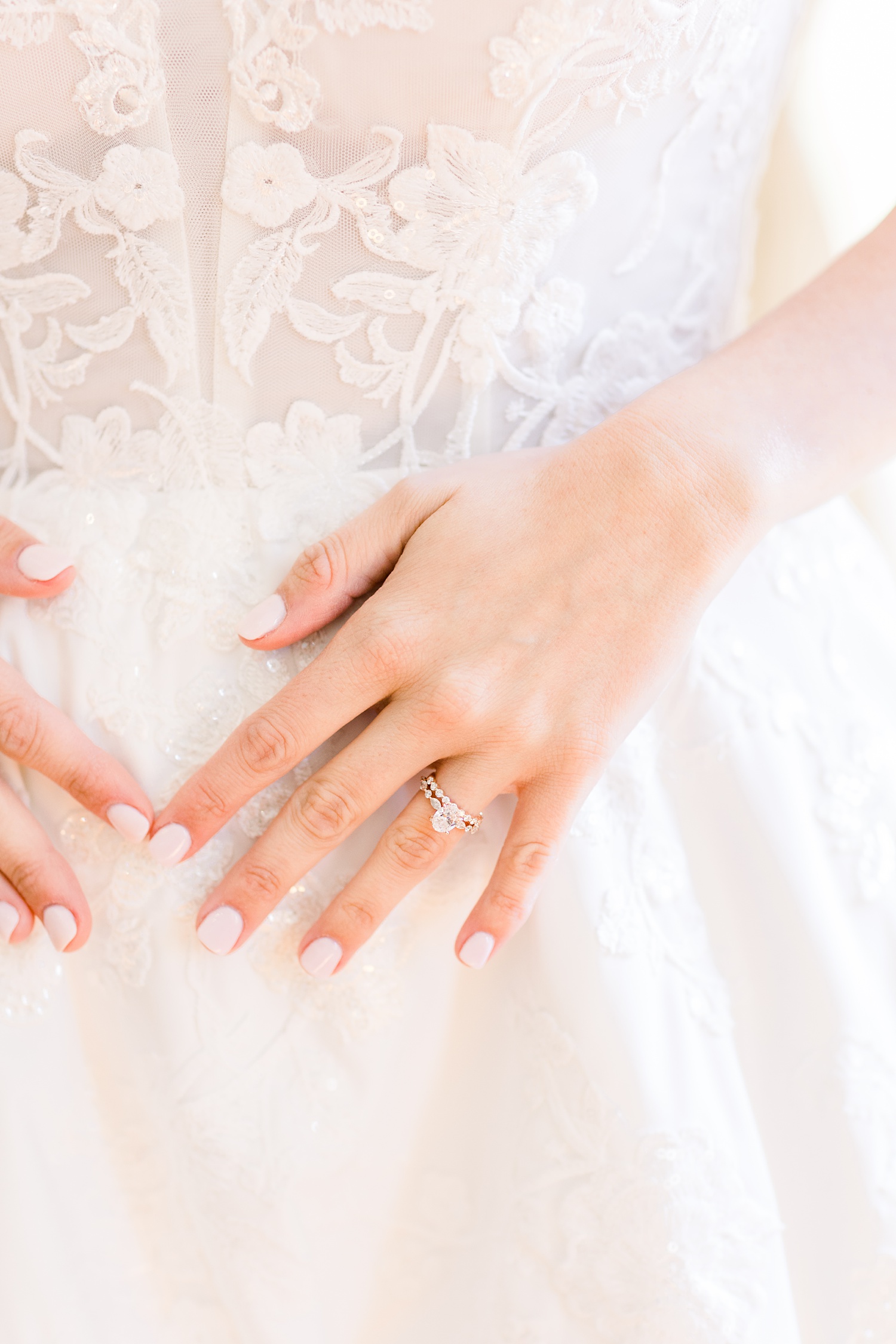 bride straightens dress out showing off engagement ring