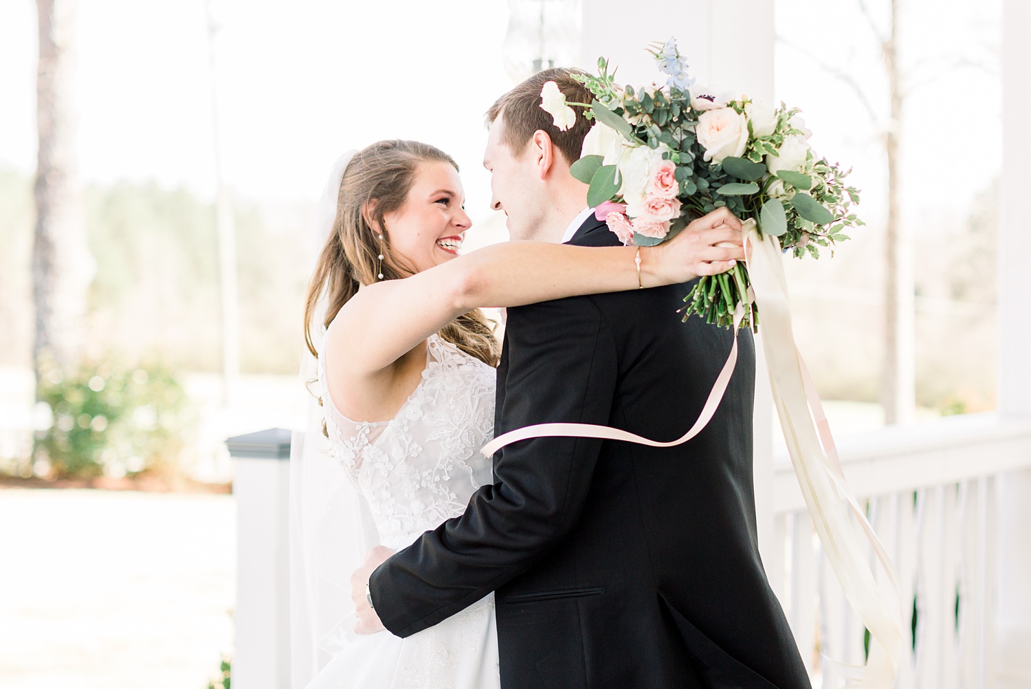 bride hugs groom with bouquet behind his head during first look