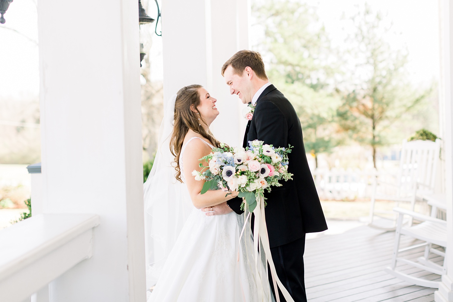 bride and groom smile together on front steps during first look