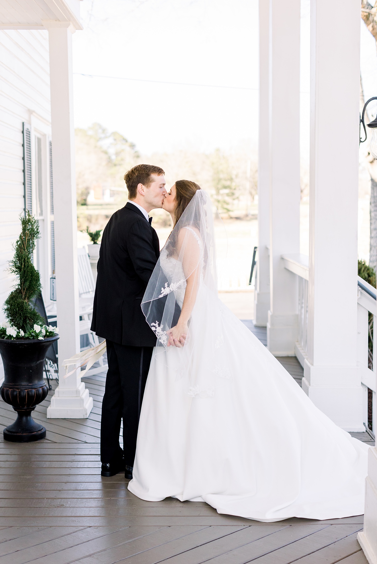 bride and groom kiss on front porch at Camelot Manor