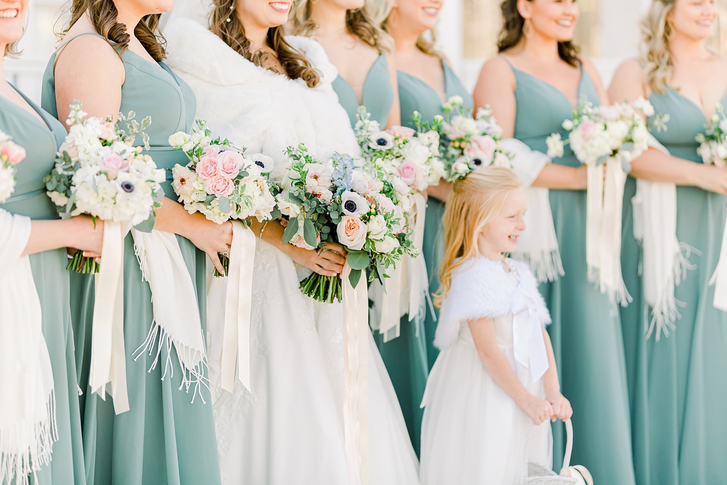bride and bridesmaids hold bouquets with ivory shawls