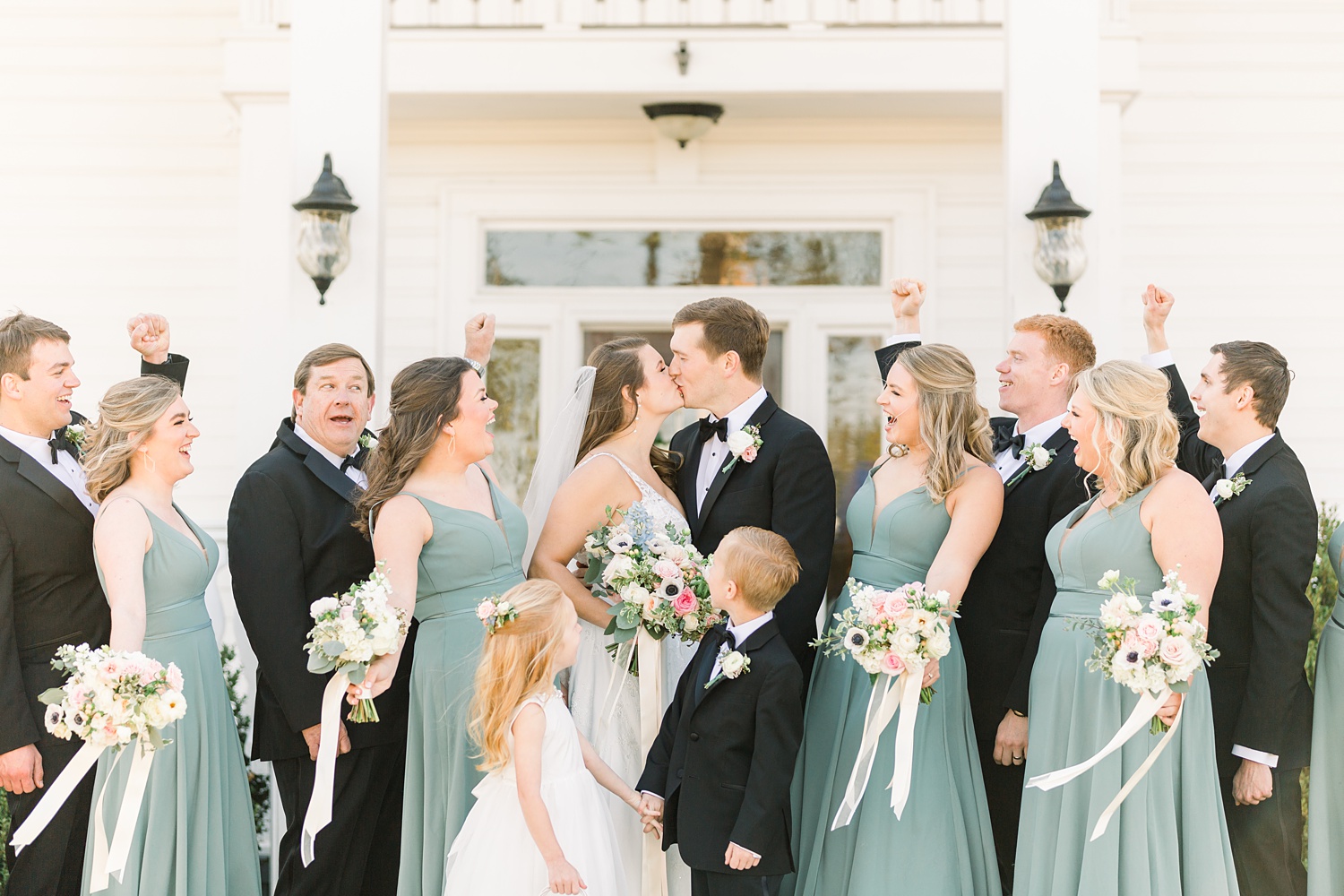 newlyweds kiss with bridal party cheering them on