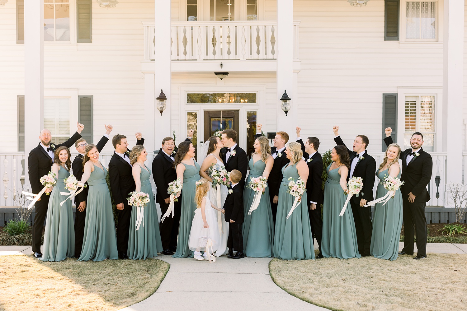 bride and groom pose outside Camelot Manor with bridal party in green and black