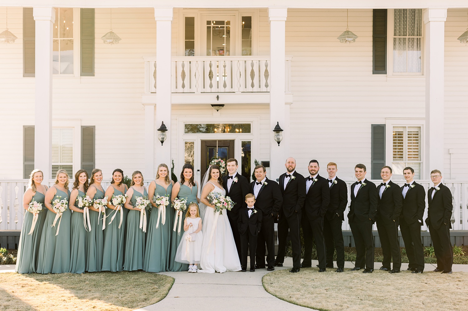 bride and groom pose outside Camelot Manor with bridal party