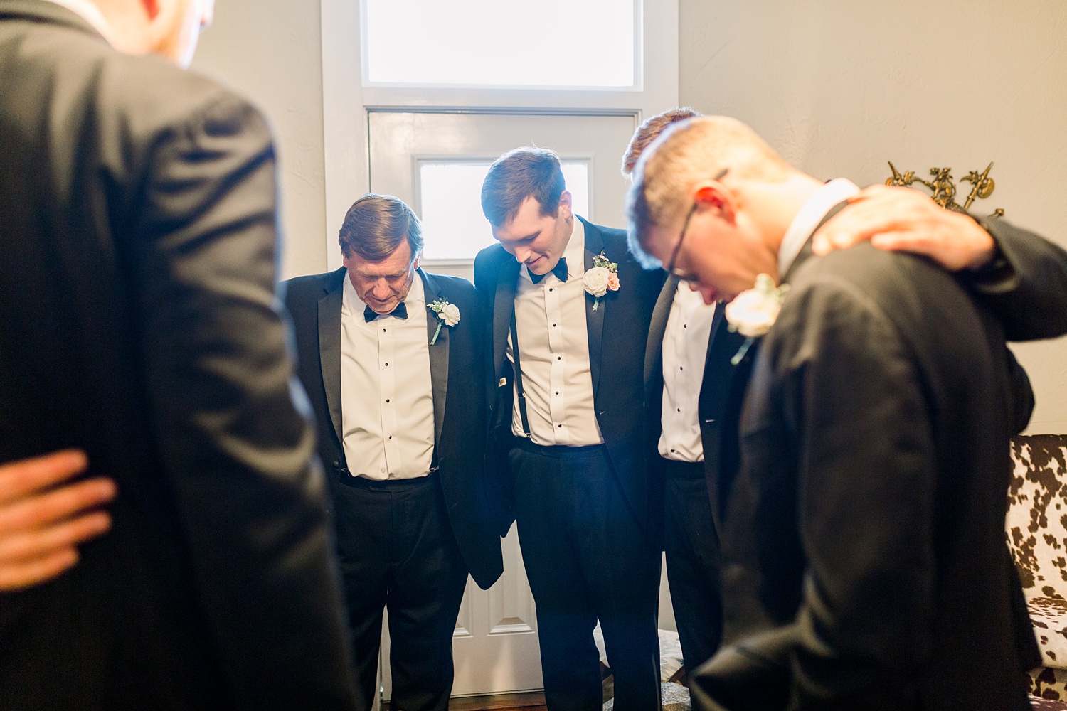 groom prays with groomsmen before wedding ceremony