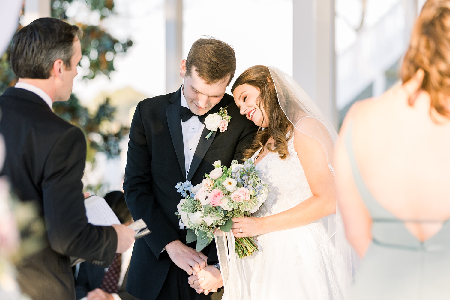 bride leans against groom during wedding ceremony