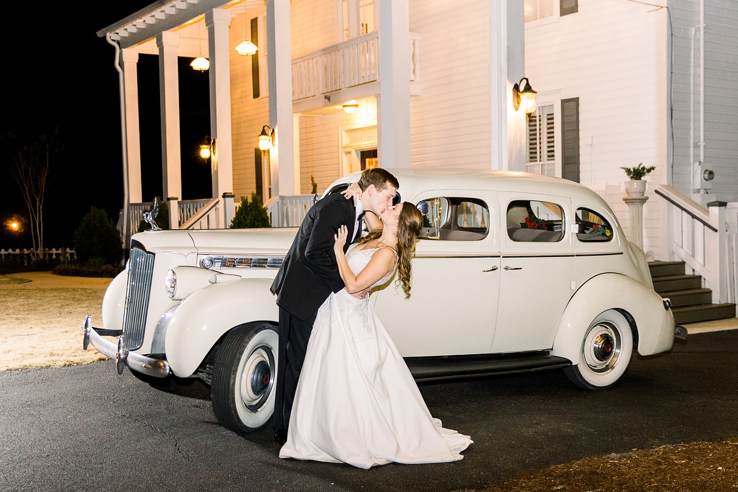 bride and groom kiss by classic car