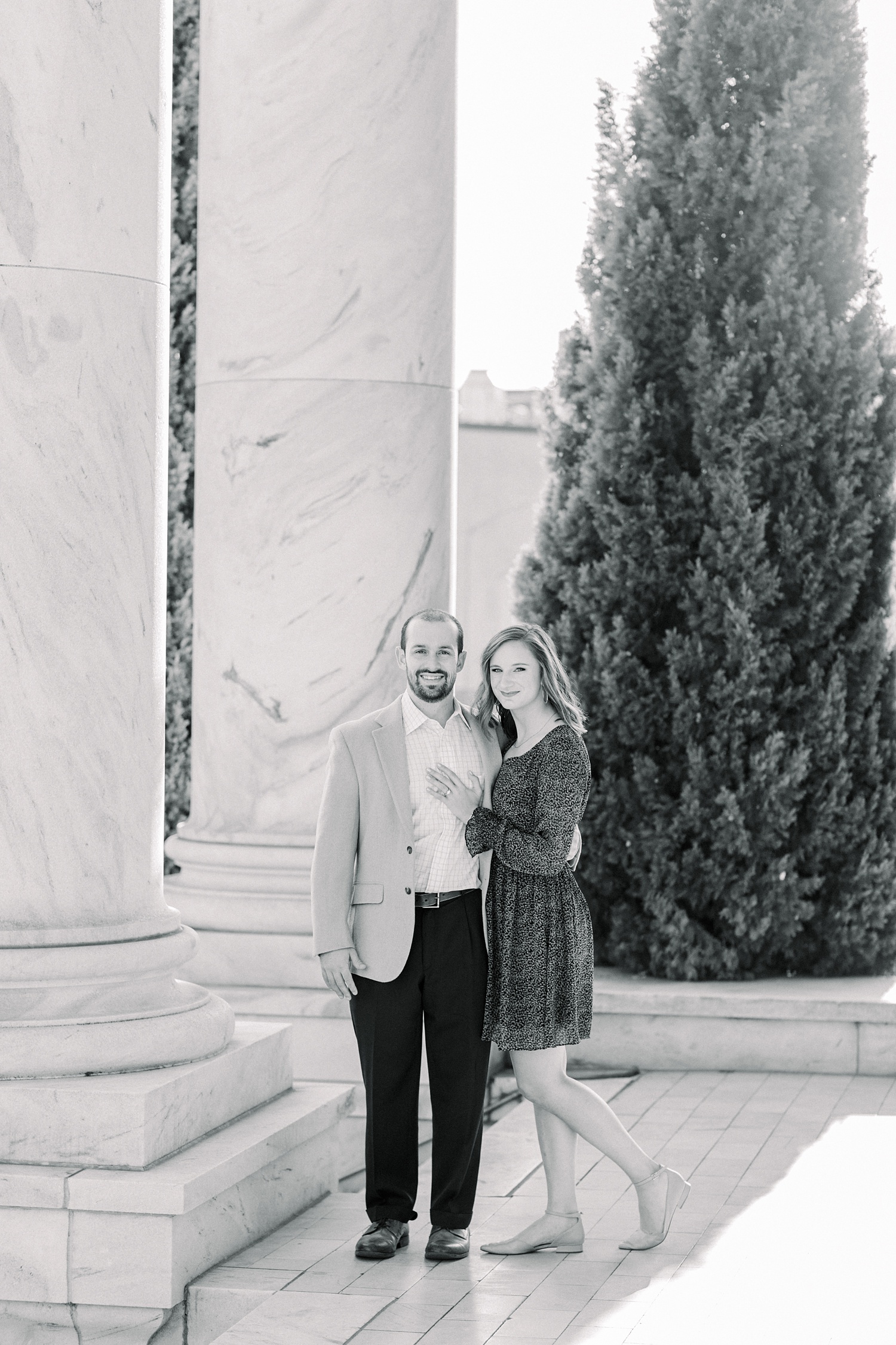 couple poses by by stone pillar in Downtown Birmingham
