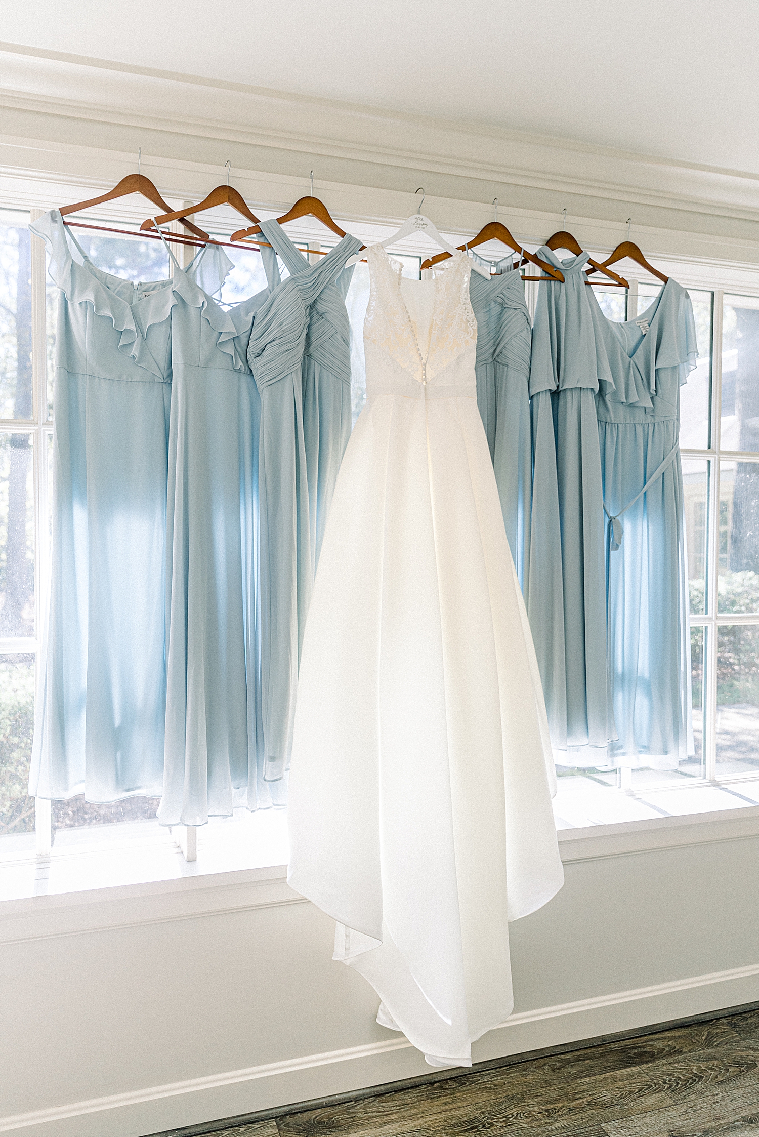 bride's dress hangs with blue bridesmaid gowns