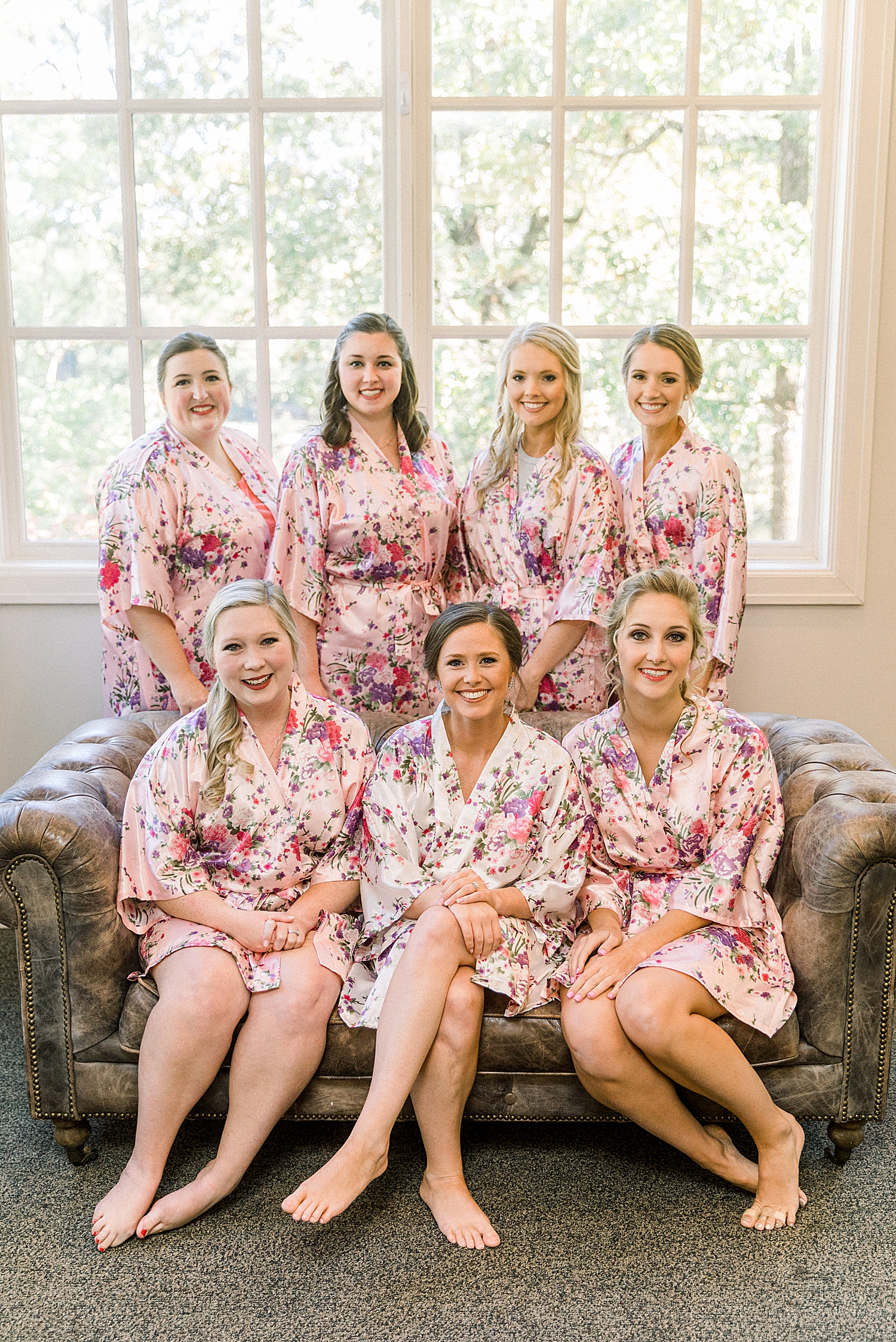 bride sits with six bridesmaids in pink robes