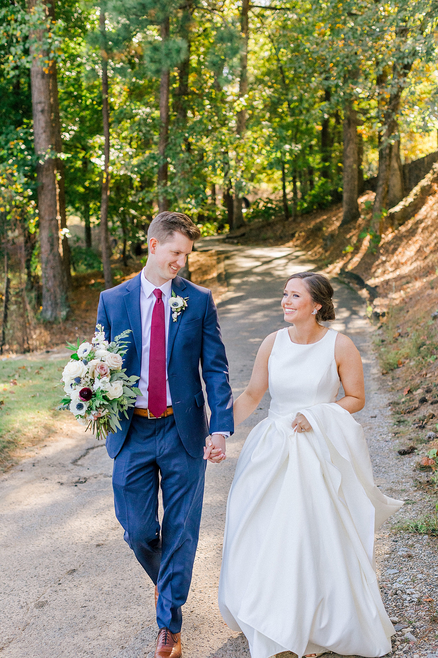 newlyweds walk through woods at Riverchase Country Club