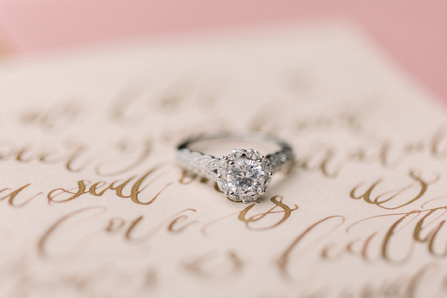 diamond ring rests on invitation with calligraphy