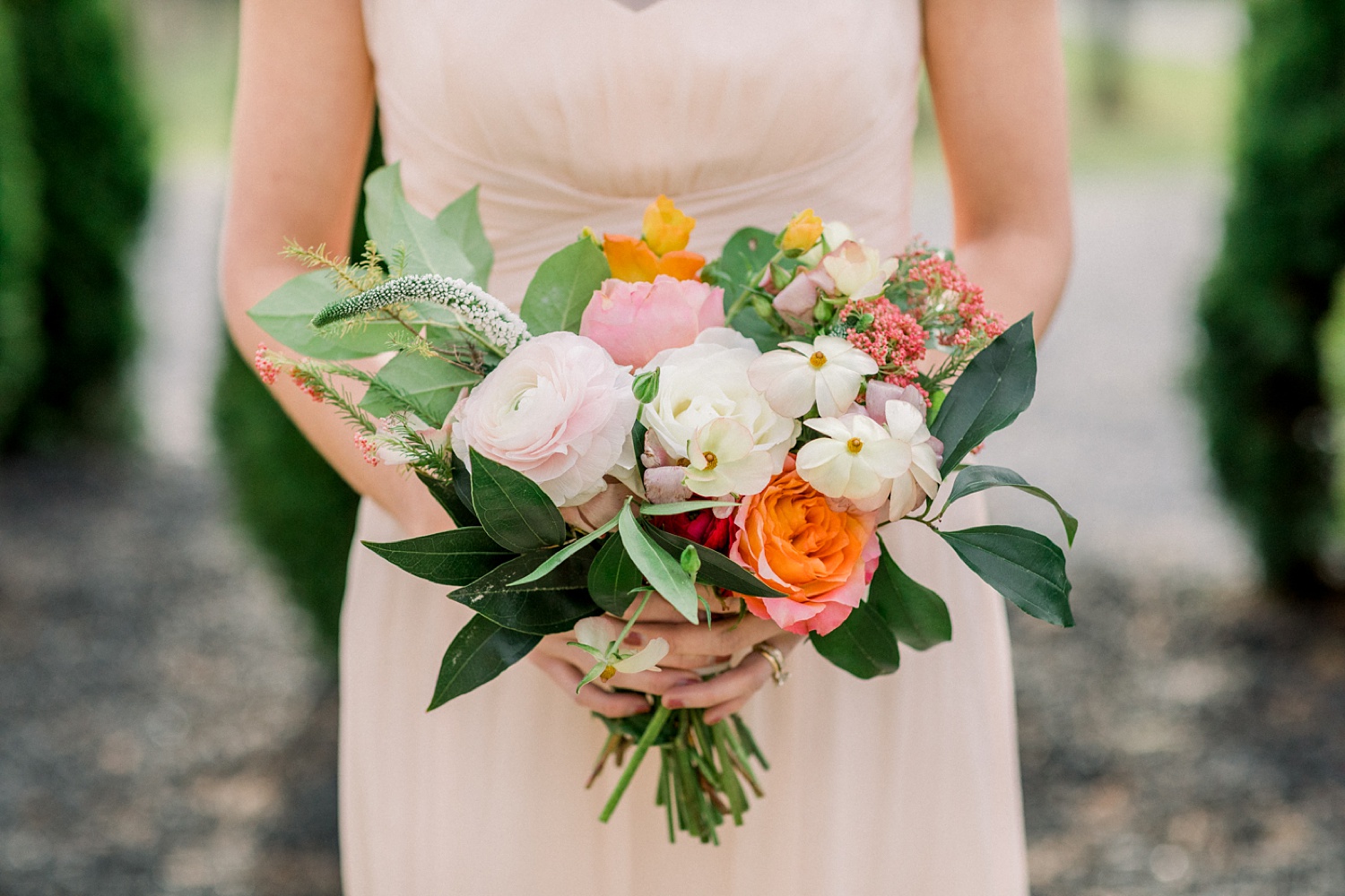 bridesmaid in pink dress holds bouquet of orange flowers