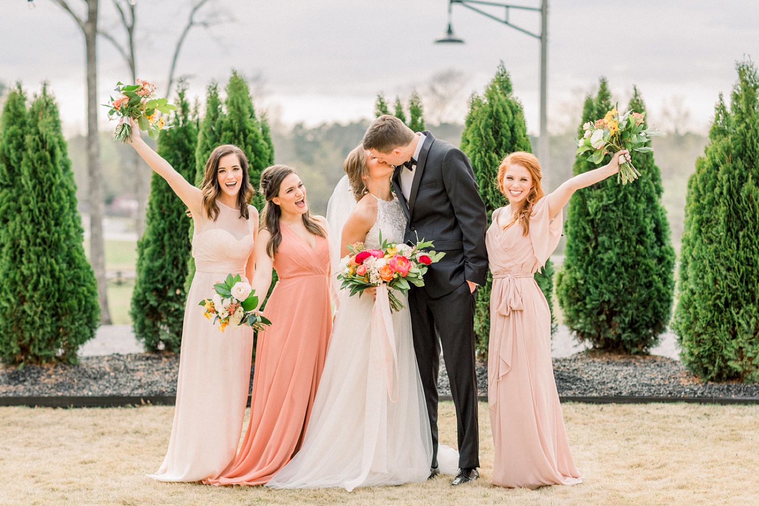 bride and groom kiss with bridesmaids at Oak Meadow Event Center