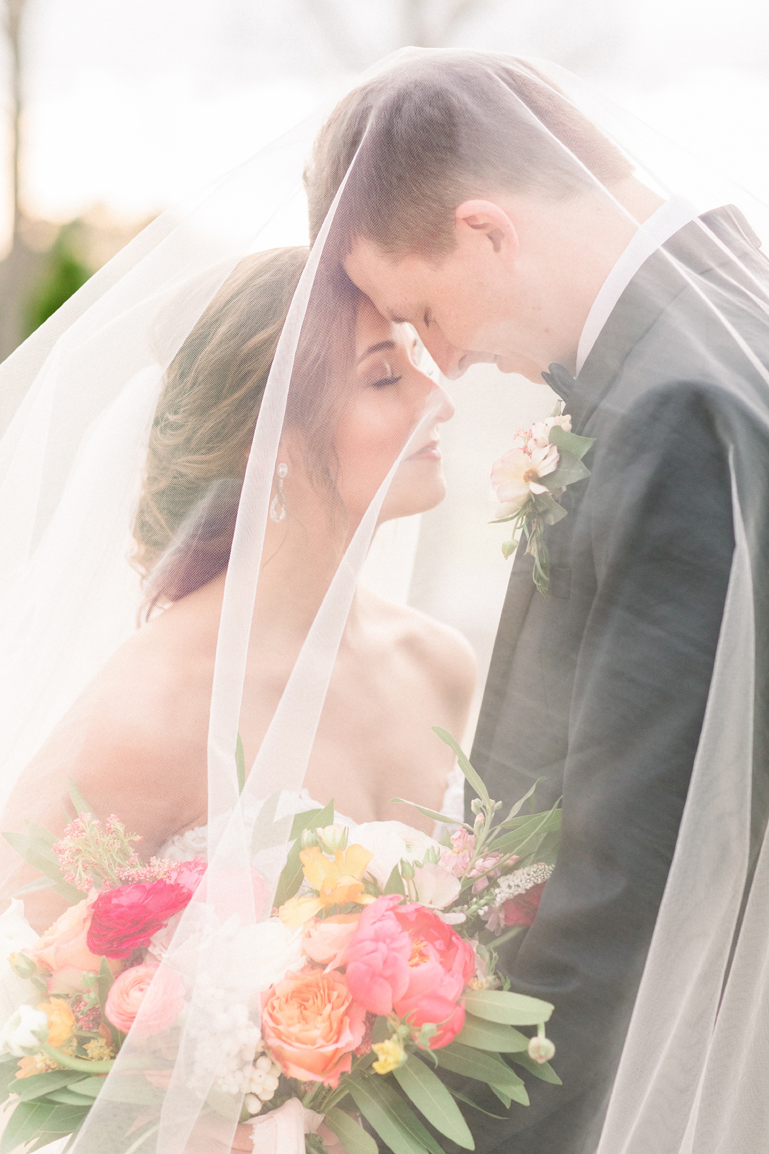 bride and groom touch foreheads under veil