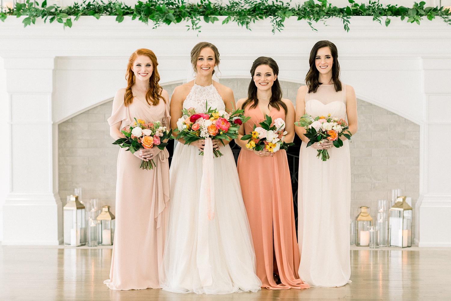 bride and bridesmaids pose by white fireplace at Oak Meadow Event Center
