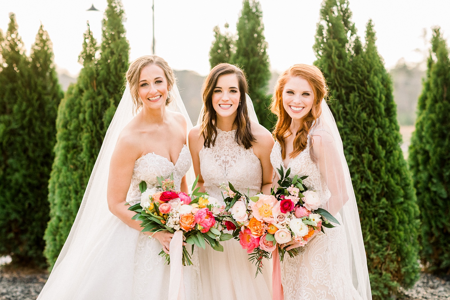 brides pose together with pink and peach flowers