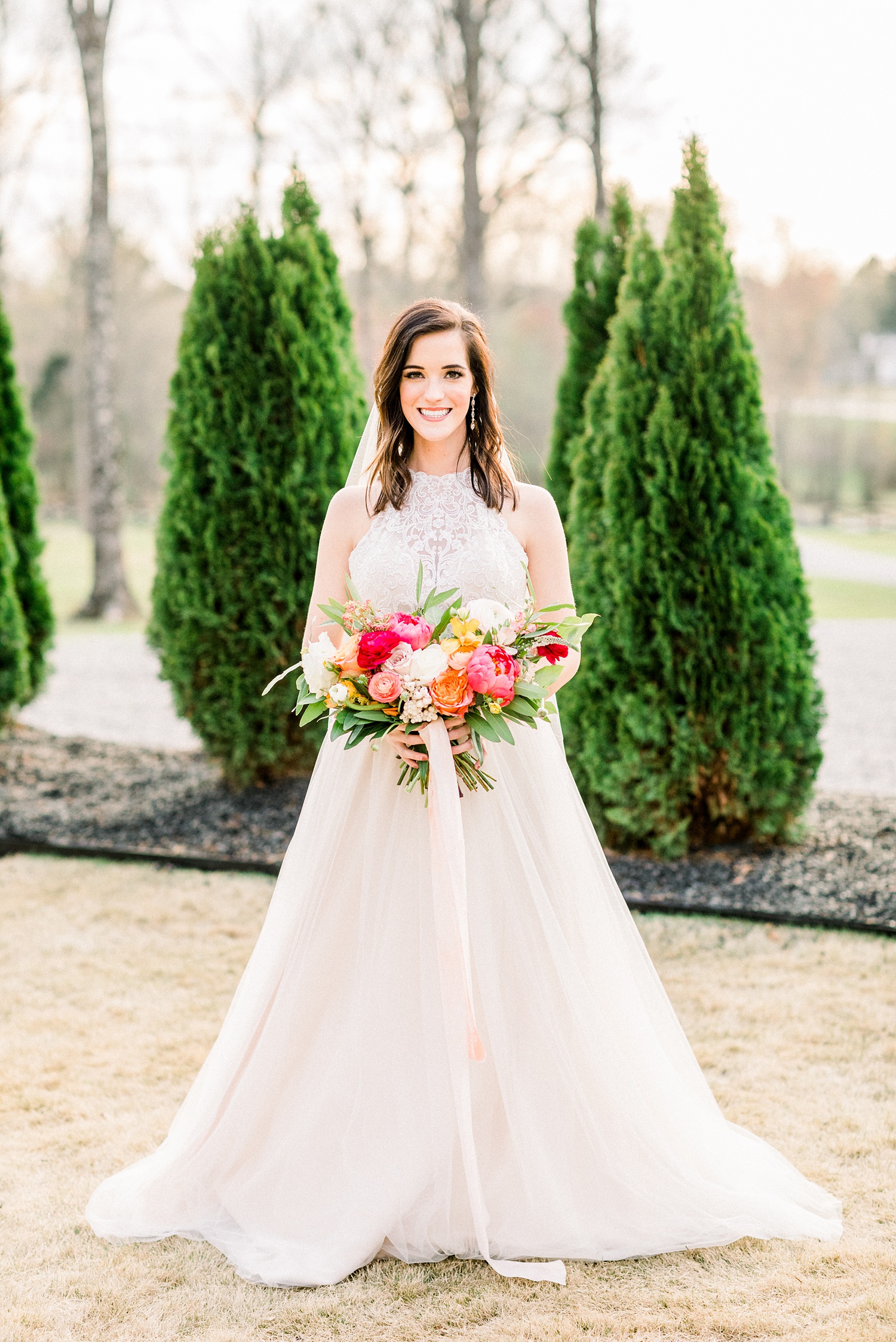 bride holds colorful bouquet at Oak Meadow Event Center