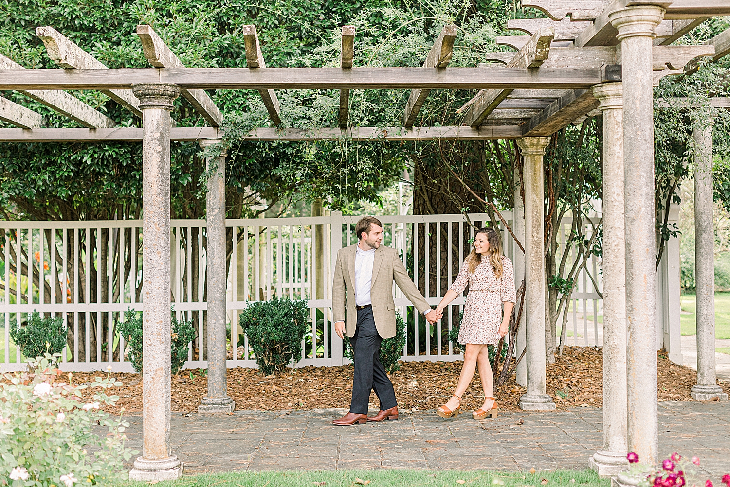 bride and groom walk through wooden arbor at Birmingham Botanical Gardens