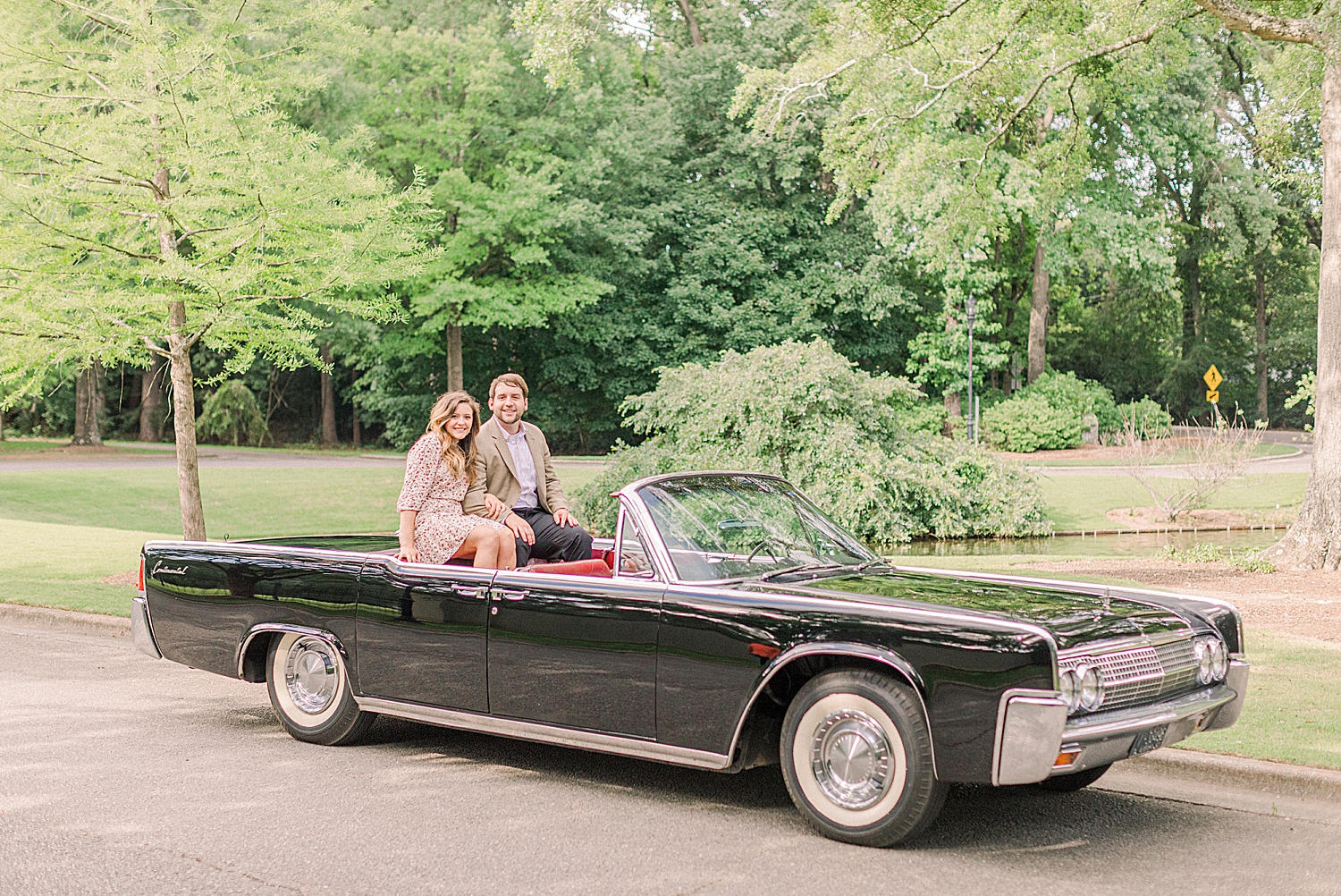 engaged couple sits in black classic car