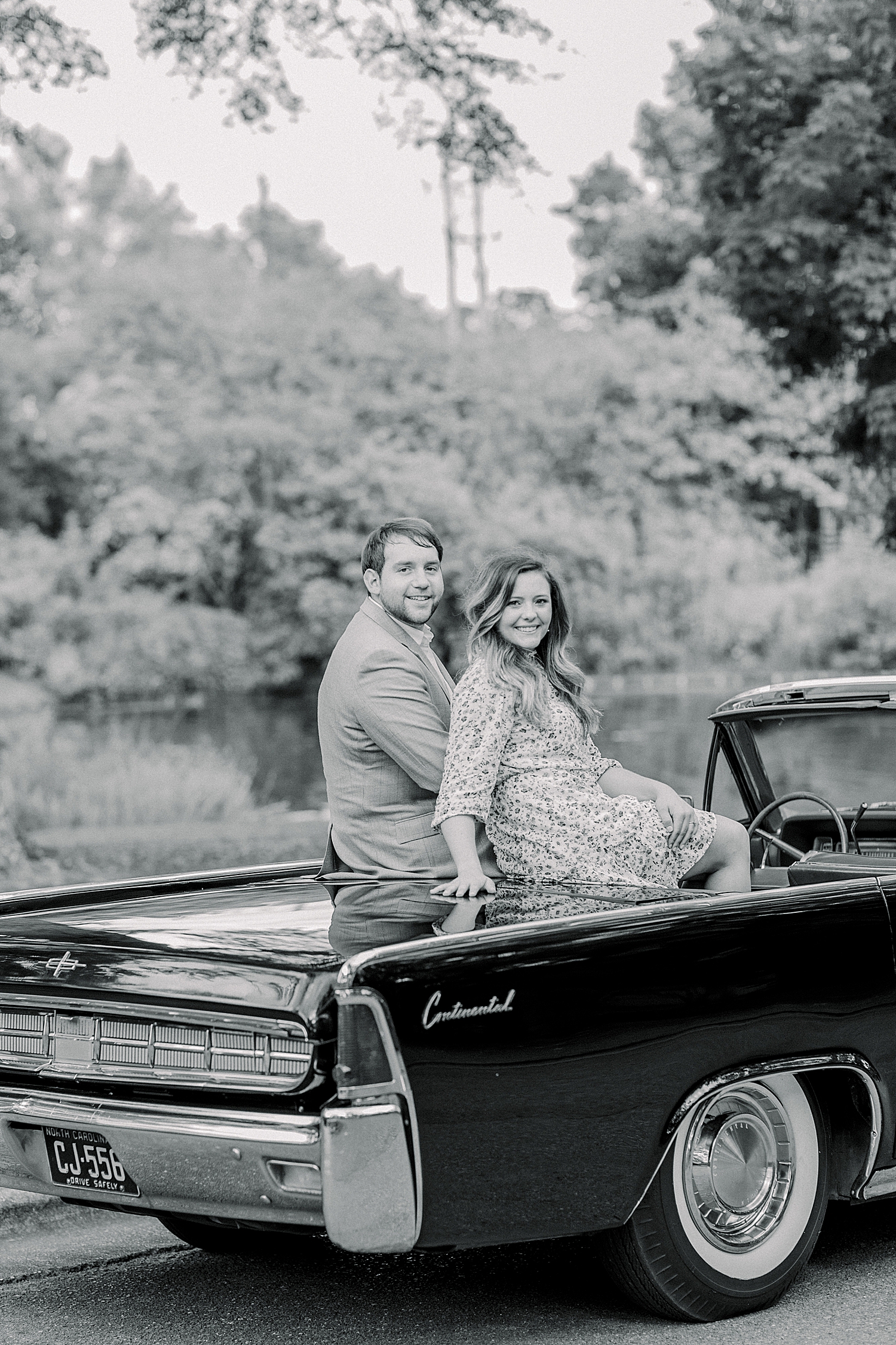 engaged couple sits on vintage black car in Birmingham Botanical Gardens