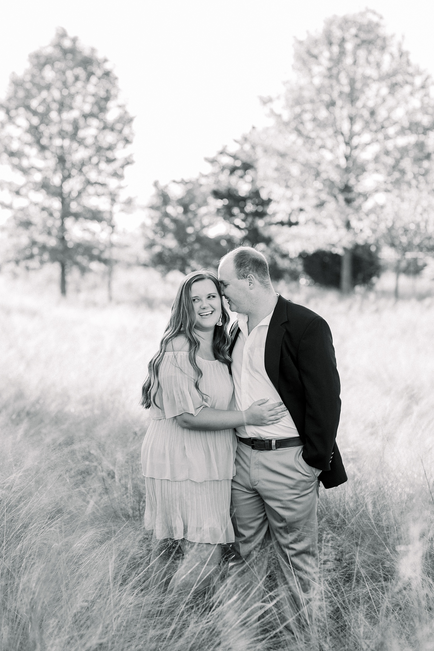 couple hugs in field during Al engagement portraits