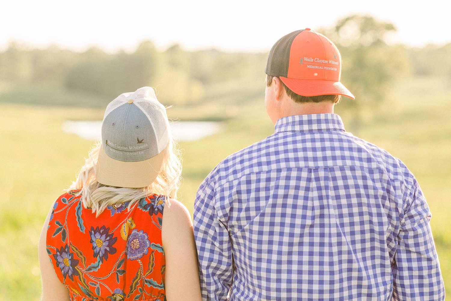 bride and groom look at lake with baseball hats on backwards