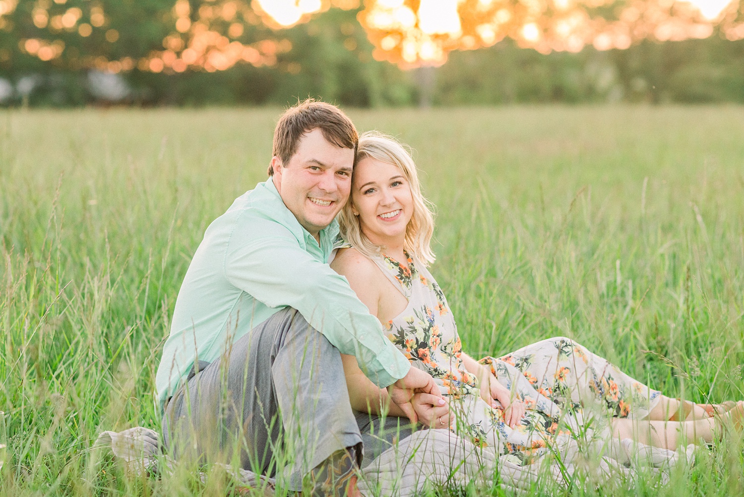 engaged couple poses at sunset in Huntsville Alabama field