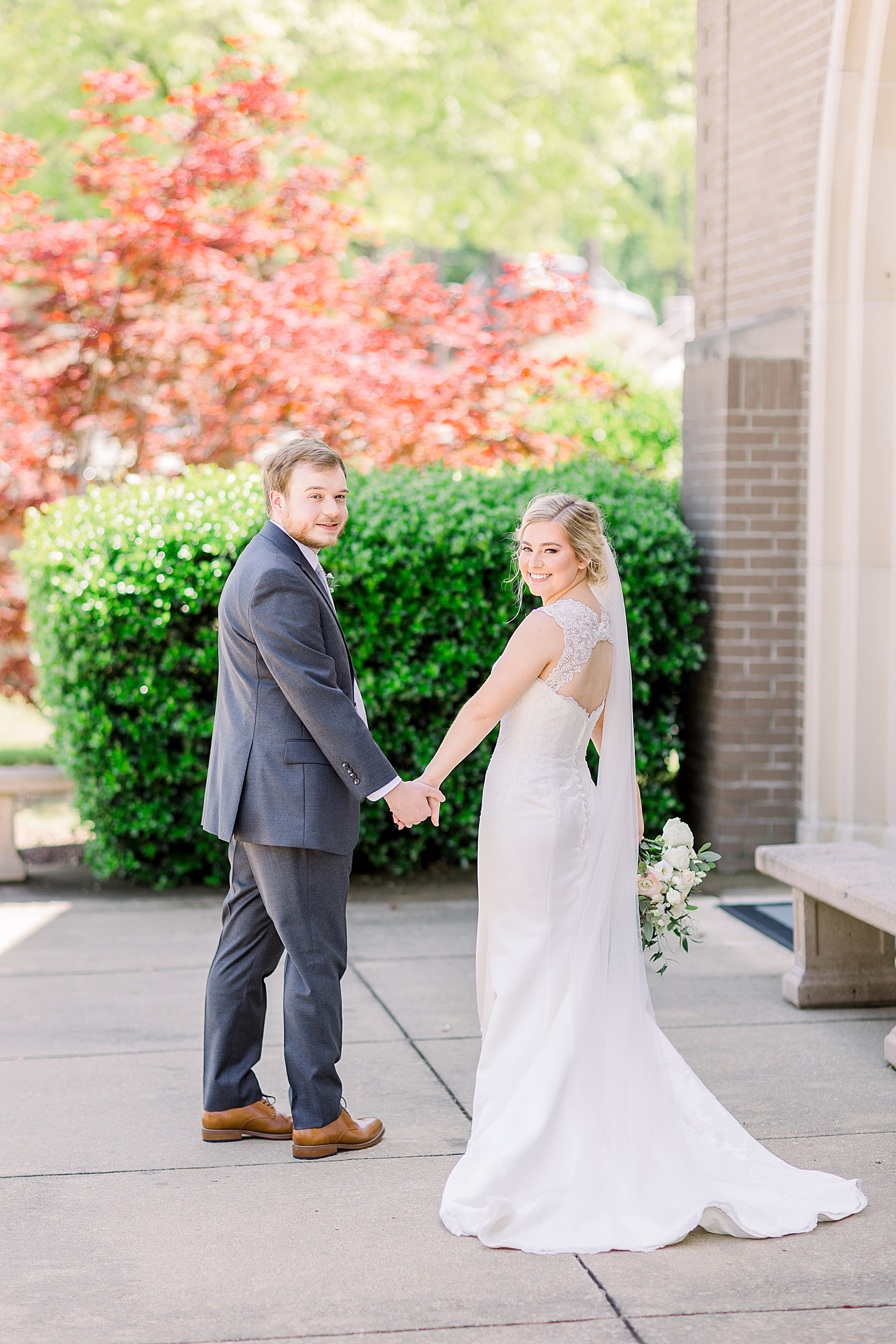 newlyweds hold hands walking by church