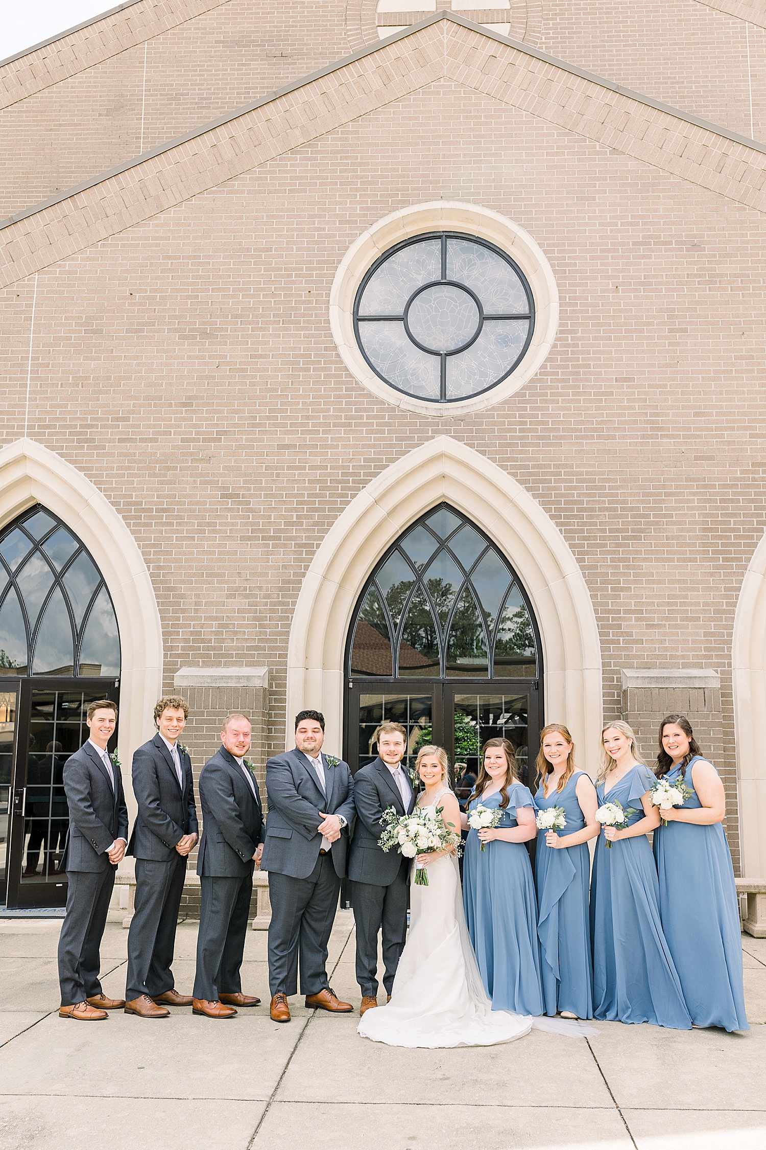 bride and groom pose with bridal party in blue gowns