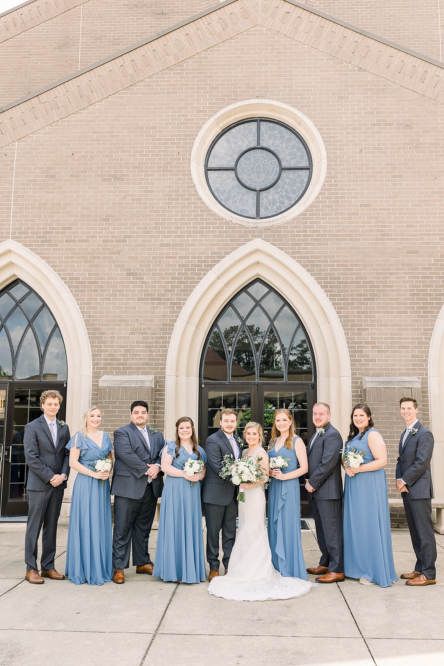 bride and groom pose with bridal party in blue and grey
