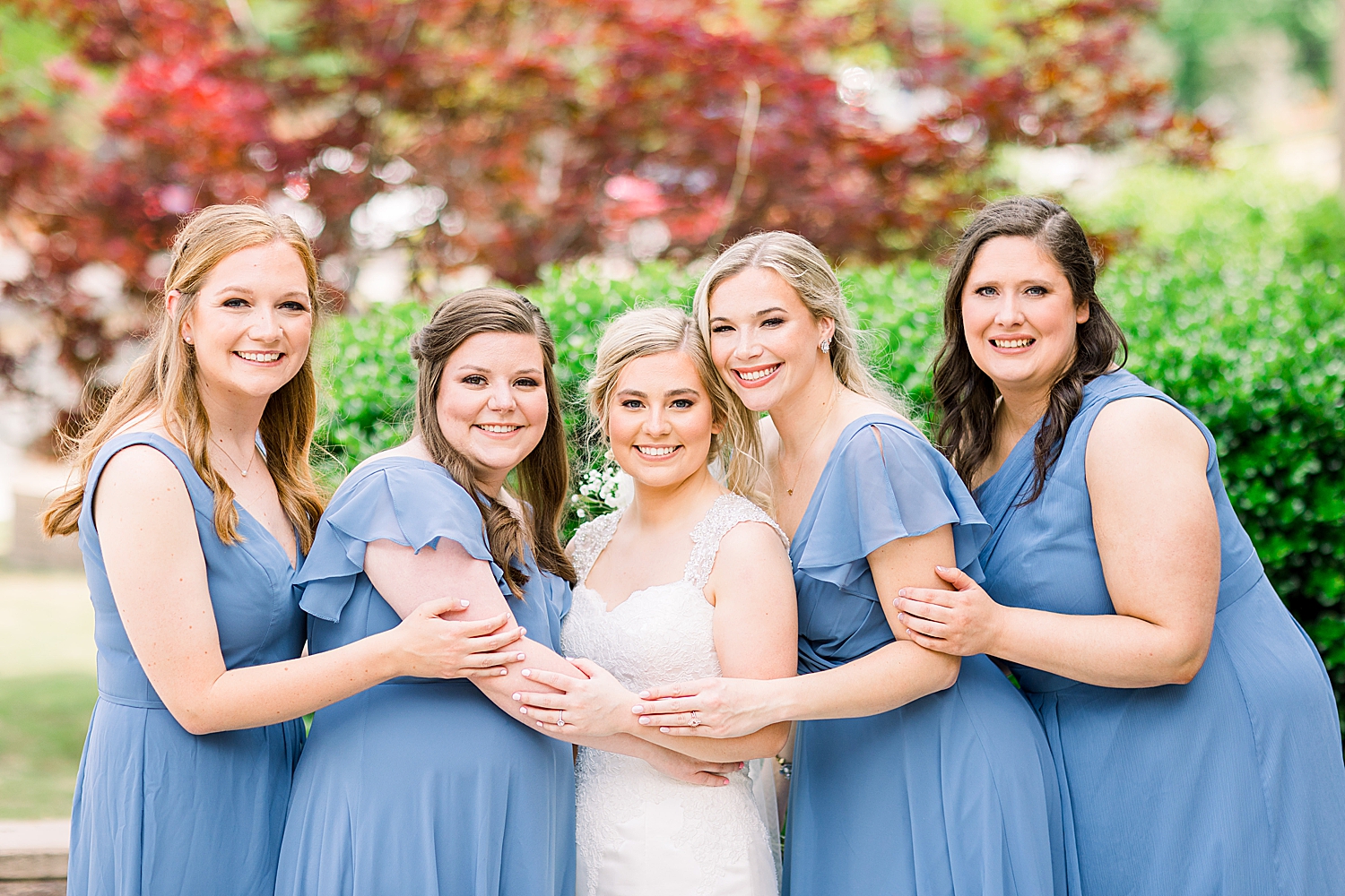 bride hugs bridesmaids in light blue gowns