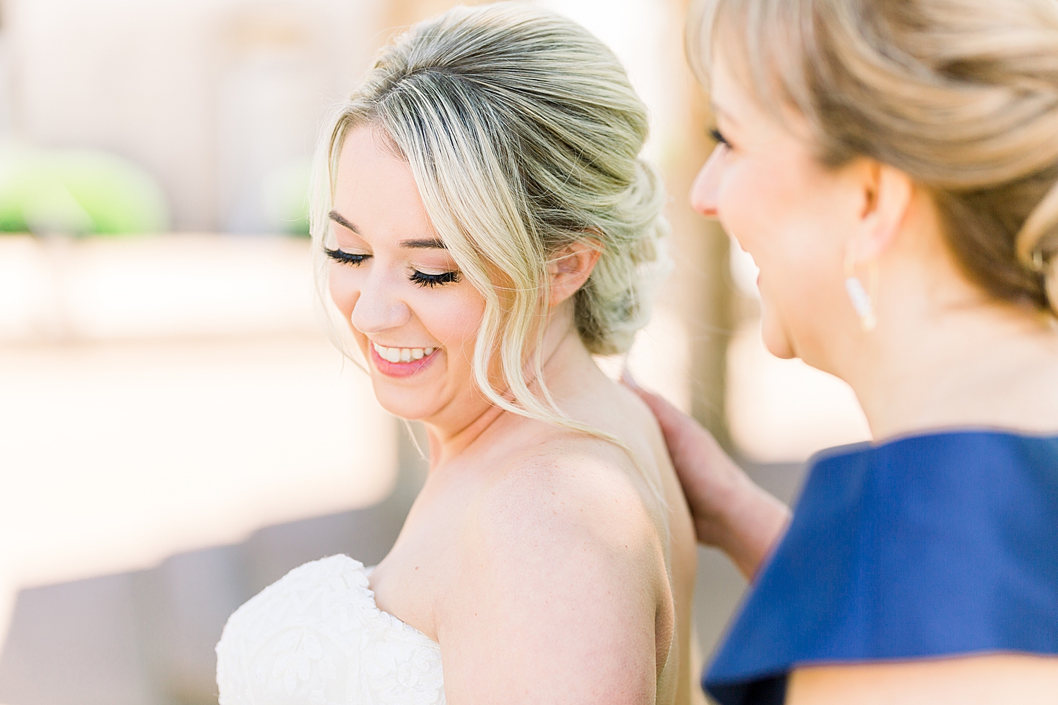 mom and bride laugh together during wedding day prep