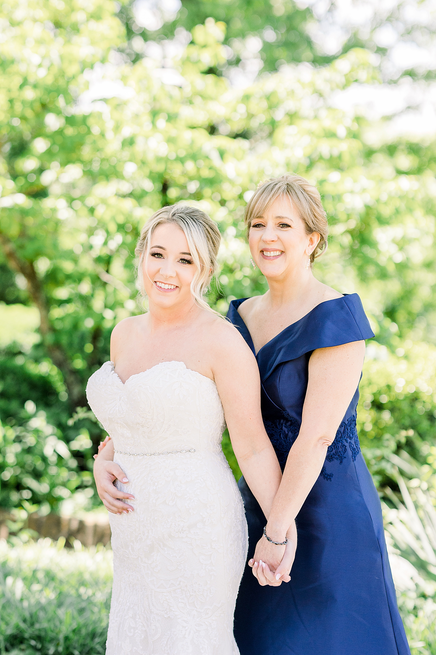 bride and mother pose together after getting wedding dress on