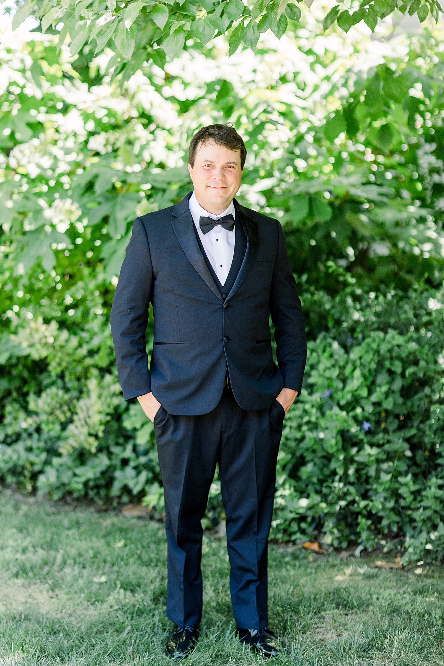 groom in classic suit poses outside Burritt on the Mountain
