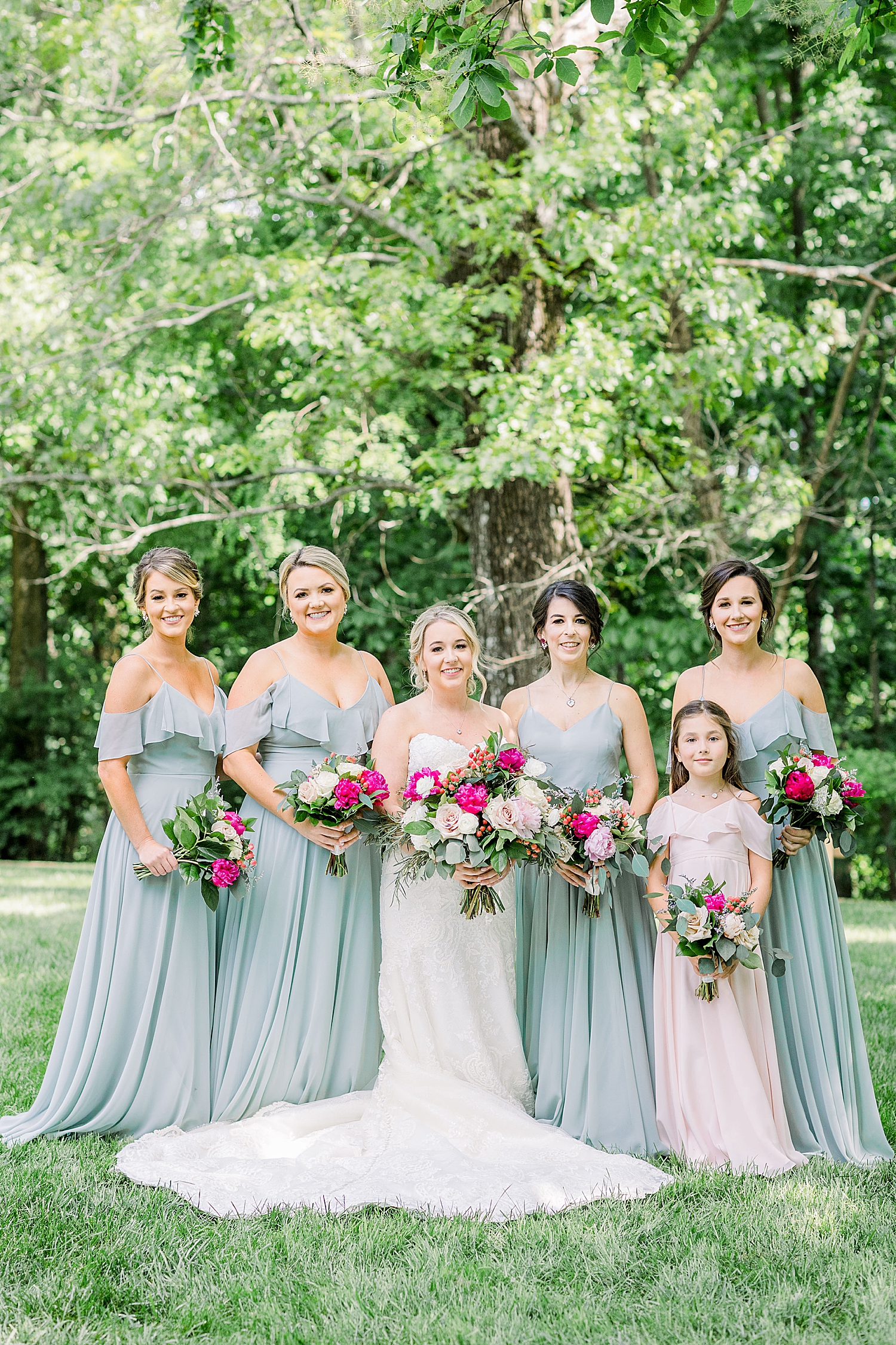 bride poses with bridesmaids in pastel green