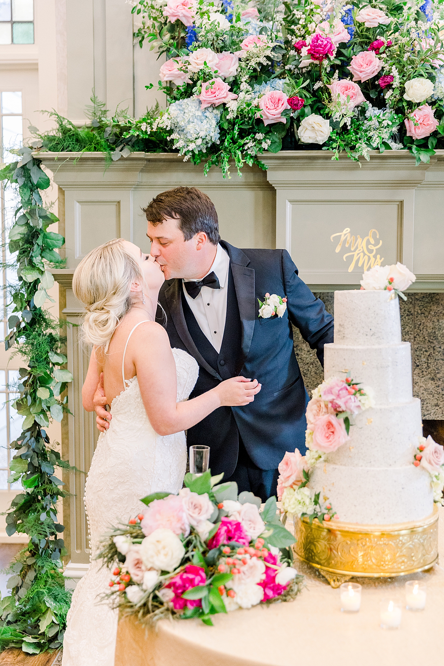 bride and groom kiss by tiered wedding cake