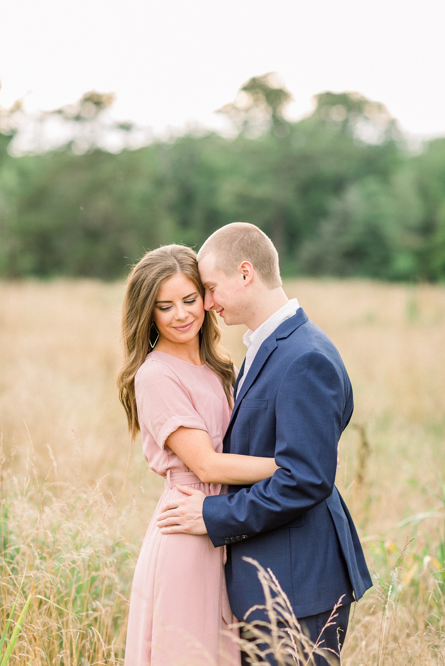 groom nuzzles bride's cheek during engagement session in tall grass